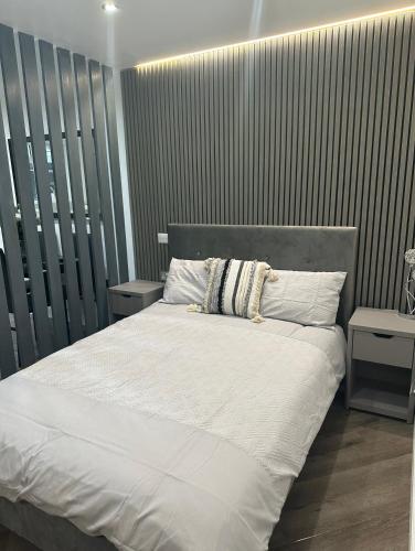 a bedroom with a large white bed with two tables at Studio T in Dagenham