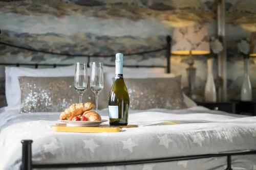 a bottle of wine and two glasses on a bed at Serendipity ~ Romantic Hideaway in Ambleside in Ambleside