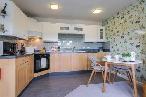a kitchen with white cabinets and a table with chairs at Serendipity ~ Romantic Hideaway in Ambleside in Ambleside