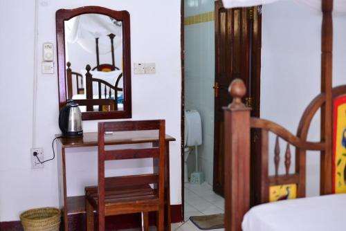a bedroom with a mirror and a table and a chair at La Neisha Hotel Zanzibar in Stone Town