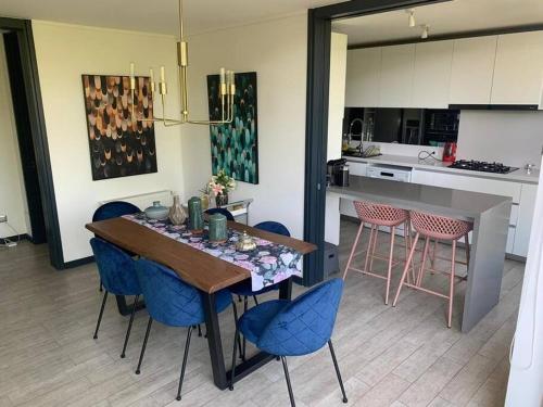 cocina con mesa de comedor y sillas azules en Spectacular Apartament in La Dehesa with Private Rooftop, en Santiago