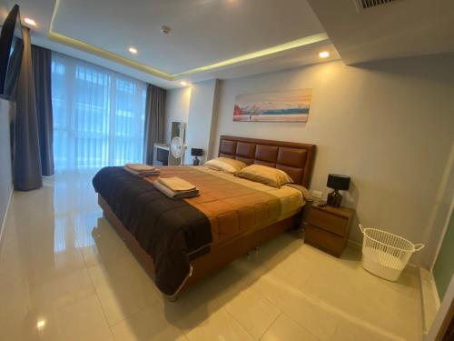 a bedroom with a bed and a large window at Large Deluxe Condo Grand Avenue Central Pattaya in Pattaya Central