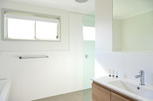 a white bathroom with a sink and a mirror at NRMA Toowoon Bay Holiday Park in The Entrance