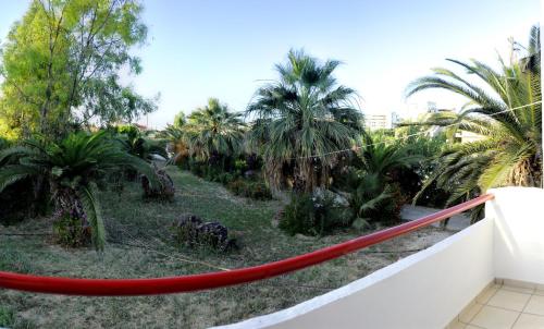 a red hammock on a balcony with palm trees at Violetta Hotel in Amoudara Herakliou