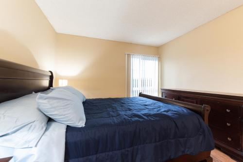 a bedroom with a bed with a blue comforter and a window at Luxurious stay near the beach in Newport Beach