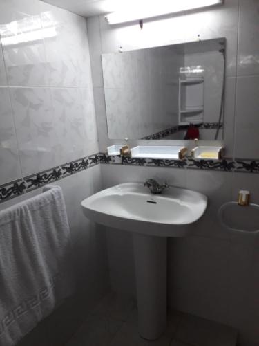 Baño blanco con lavabo y espejo en Appartement Moderne 3 Chambres, en Fez