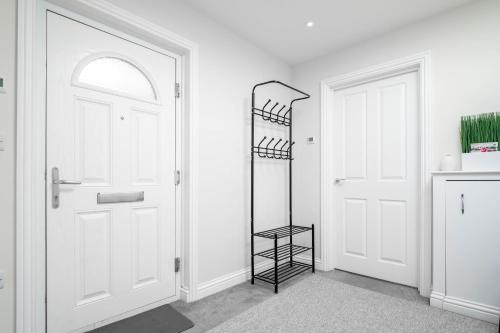 a white hallway with a white door and a black shelf at Garland Penthouse - Large 2 bed 2 bath self contained flat in Redhill