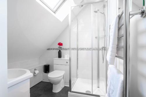 a white bathroom with a shower and a toilet at Garland Penthouse in Redhill