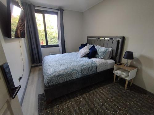 a bedroom with a bed with blue pillows and a window at Costanera Bed & Breakfast in Santiago