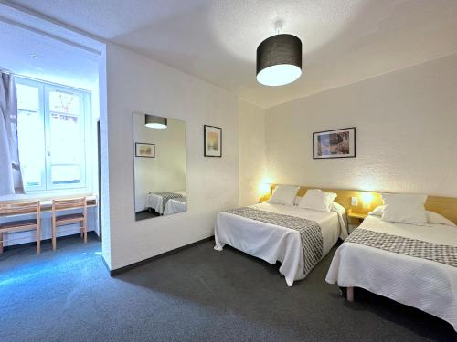 Habitación de hotel con 2 camas y espejo en Hôtel Peyramale, en Lourdes