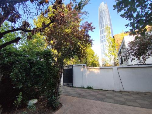 a tree next to a white fence and a building at Costanera Bed & Breakfast in Santiago