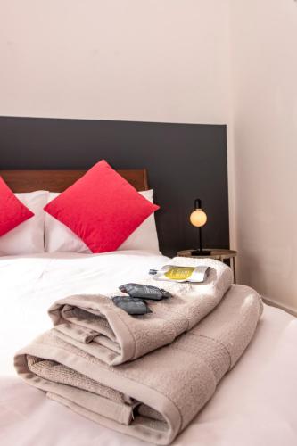 a blanket sitting on top of a bed with red pillows at Architect Designed Lodge in Dunecht