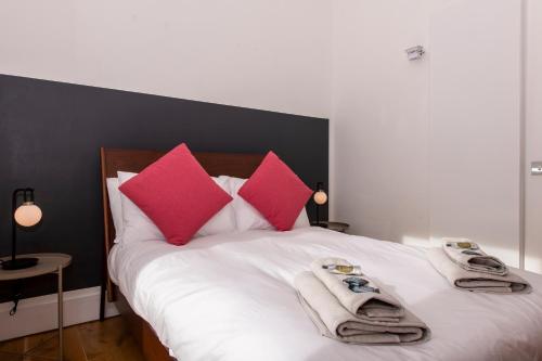 a bed with red and pink pillows and towels on it at Architect Designed Lodge in Dunecht