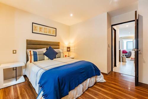 a bedroom with a large bed with a blue blanket at Moderno departamento en el corazón de la Roma in Mexico City