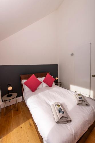 a bedroom with a white bed with red pillows at Architect Designed Lodge in Dunecht