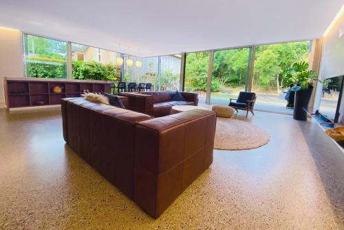 a large living room with a brown leather couch at Dune Ten by Kingscliff Accommodation in Fingal Head