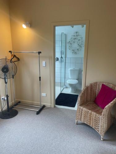 a bathroom with a toilet and a chair and a shower at Kaingarua Retreat in Kerikeri