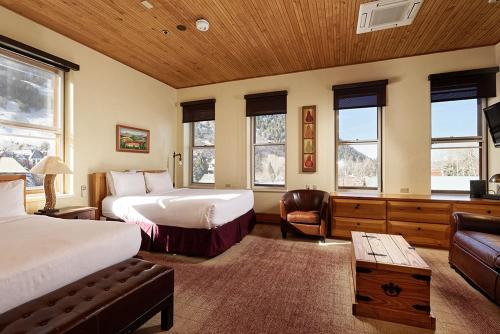 a bedroom with two beds and a couch and windows at Independence Square Unit 313, Downtown Hotel Room in Aspen with Rooftop Hot Tub in Aspen