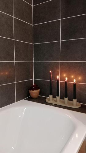 La salle de bains est pourvue d'une baignoire et de bougies sur un mur. dans l'établissement Appartement, à Saint-Denis