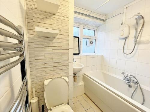 a bathroom with a toilet and a tub and a sink at Beautiful Modern Apt (Sleeps 5) in Croydon