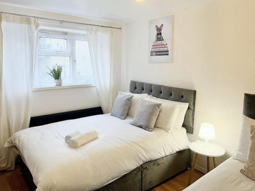 um quarto com uma grande cama branca e uma janela em Beautiful Modern Apt (Sleeps 5) em Croydon