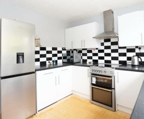 a kitchen with white cabinets and a black and white checkered wall at The Dunstable House in Houghton Regis