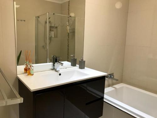 a bathroom with a sink and a bath tub at Melbourne Inner City Holiday Home Near CBD & Flemington in Melbourne
