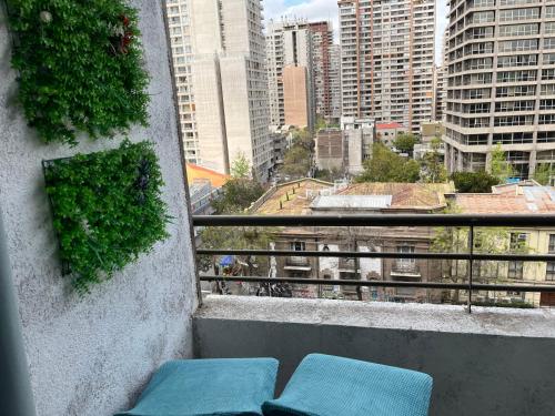 balcón con 2 sillas azules y vistas a la ciudad en Apartment Relocation San Isidro, en Santiago