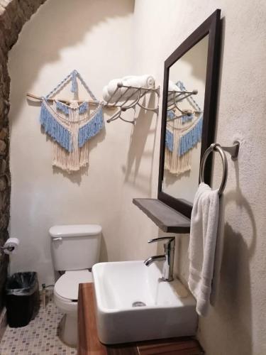 a bathroom with a sink and a mirror and a toilet at Grann Posada Xilitla in Xilitla