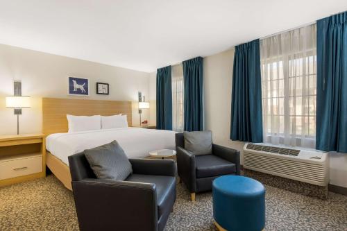 ein Hotelzimmer mit einem Bett und zwei Stühlen in der Unterkunft Sonesta ES Suites Charlotte Arrowood in Charlotte