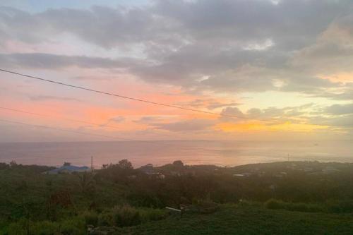a sunset over a field with the ocean in the background at TAG DA Paradise Inn in Riversdale