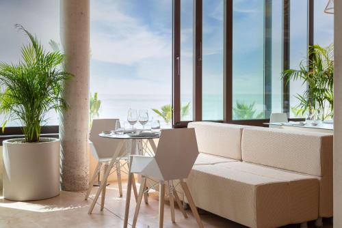 a living room with a couch and a table with wine glasses at Higuerón Hotel Curio Collection by Hilton in Fuengirola