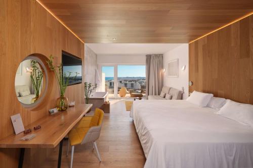 a hotel room with a large bed and a desk at Higuerón Hotel Curio Collection by Hilton in Fuengirola