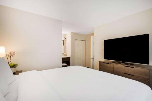 a white bedroom with a large bed and a flat screen tv at Sonesta ES Suites Denver South Park Meadows in Lone Tree