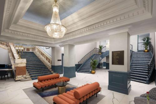 a lobby with benches and stairs with a chandelier at DoubleTree By Hilton Brighton Metropole in Brighton & Hove