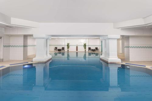 a large swimming pool with columns in a building at DoubleTree By Hilton Brighton Metropole in Brighton & Hove