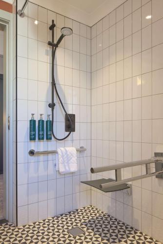 a bathroom with a shower with white tiles at DoubleTree By Hilton Brighton Metropole in Brighton & Hove