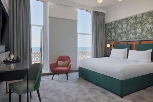 a bedroom with a large bed and a desk and chair at DoubleTree By Hilton Brighton Metropole in Brighton & Hove
