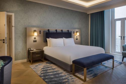 a bedroom with a large white bed and a chair at DoubleTree By Hilton Brighton Metropole in Brighton & Hove
