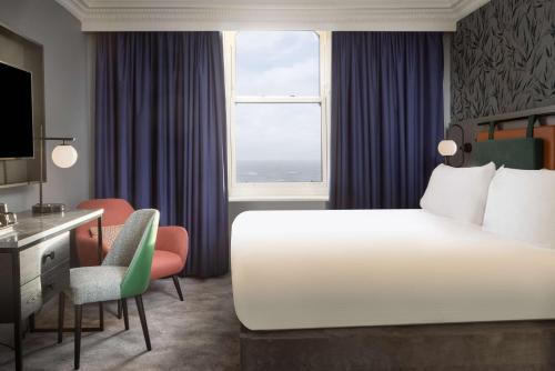 a hotel room with a bed and a desk and a window at DoubleTree By Hilton Brighton Metropole in Brighton & Hove