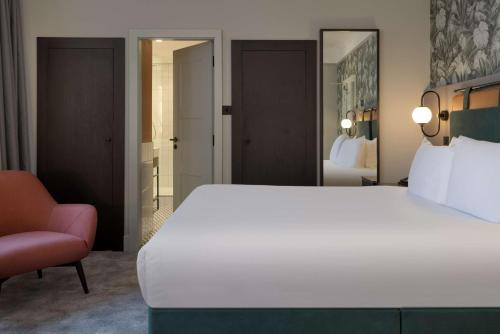 a bedroom with a large white bed and a chair at DoubleTree By Hilton Brighton Metropole in Brighton & Hove
