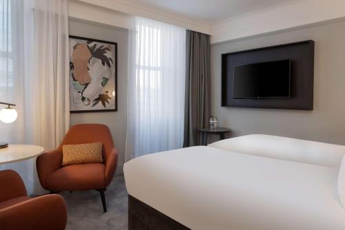 a hotel room with a bed and a chair and a television at DoubleTree By Hilton Brighton Metropole in Brighton & Hove