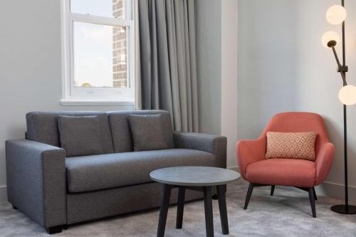 a living room with a couch and a chair and a table at DoubleTree By Hilton Brighton Metropole in Brighton & Hove