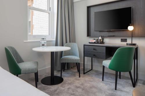a hotel room with a table and chairs and a tv at DoubleTree By Hilton Brighton Metropole in Brighton & Hove