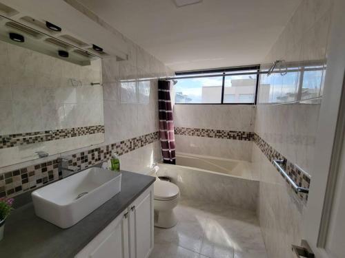 La salle de bains est pourvue d'un lavabo, d'une baignoire et de toilettes. dans l'établissement Lujoso apartamento en Bellavista, à Quito