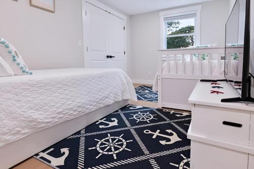 een slaapkamer met een wit bed en een zwart-wit tapijt bij Renovated & Sophisticated Home Near Beach & Shops! in Barnstable