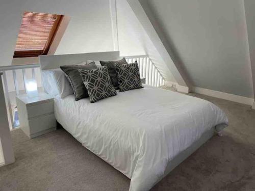 um quarto com uma cama branca com almofadas em Stylish Property in Nuneaton em Nuneaton