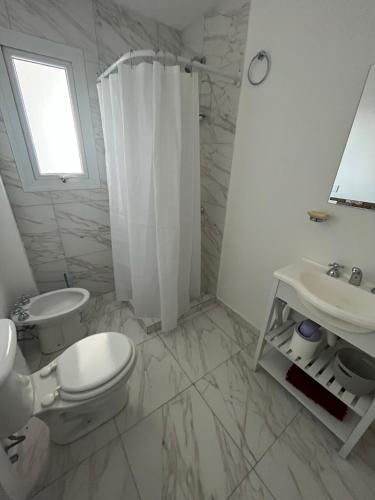 a white bathroom with a toilet and a sink at Departamento nuevo con balcón in Olavarría