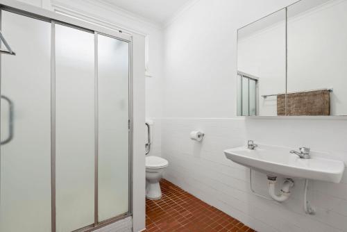 Un baño blanco con lavabo e inodoro. en Surfside, en Point Lonsdale