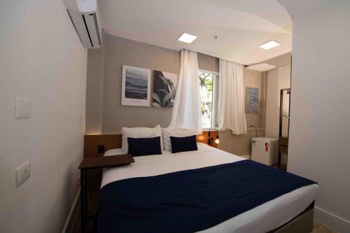 a bedroom with a large bed with blue and white sheets at Leblon Design Hotel in Rio de Janeiro
